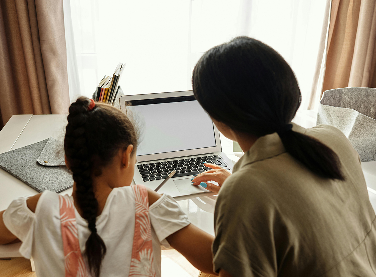 Ein Kind und eine Person sitzen vor einem Laptop